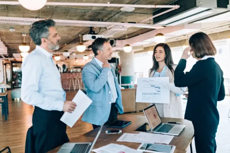 Sales team discussing reports around a desk